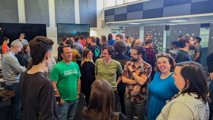 A crowd of people mingle while a group talk to The Phil Spencer. One of said group is pulling quite the face at the camera. How dare she.