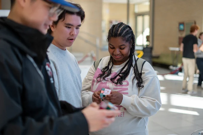 Three students attempting to solve rubik's cubes.
