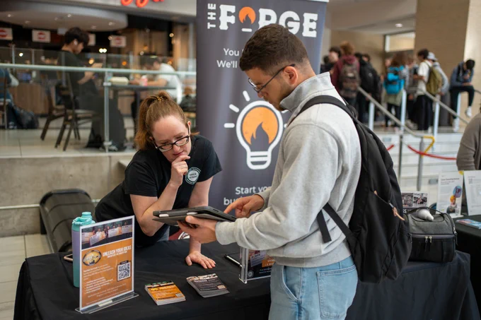 Student learning about The Forge at a booth.