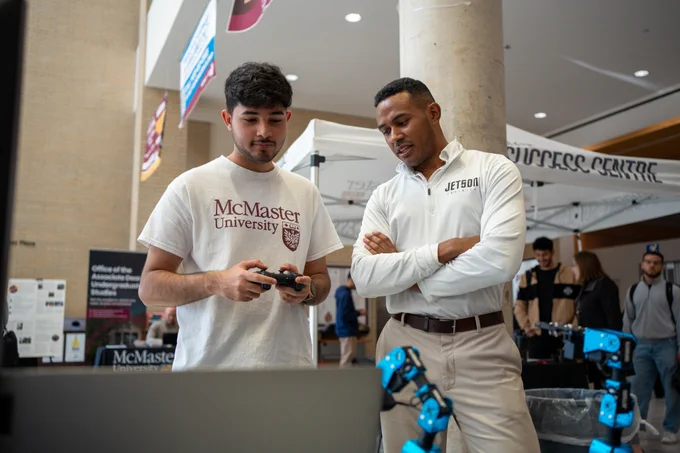 Student learning how to use a robotic arm with help from startup founder.