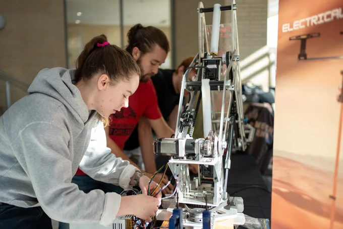 Two students working with a robotic arm.
