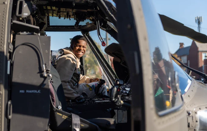 A student sits in a Black Hawk helicopter and smiles. 