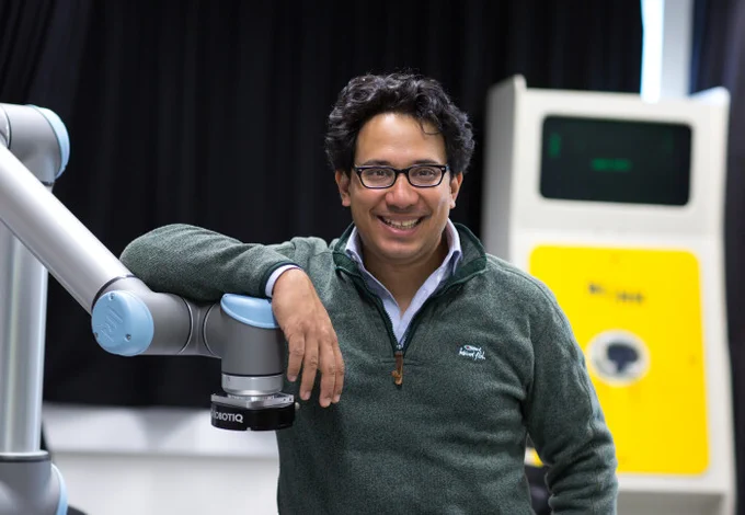 Professor Aldo Faisal leaning on equipment in a lab.