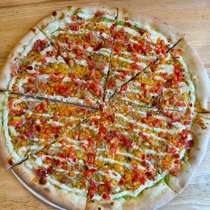 A picture of the full Turkey Roast Ghost pizza with A description of the Turkey Roast Ghost: mozzarella, avocado creme, turkey, bacon, ghost pepper cheese, topped with ranch and diced tomatoes