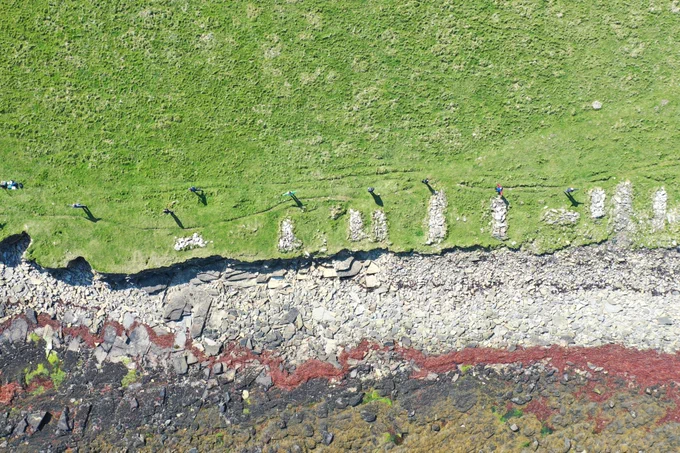 Schoolchildren from Stronsay School line up beside Kelping steethes or drying walls showing the possible coast in 2050. 