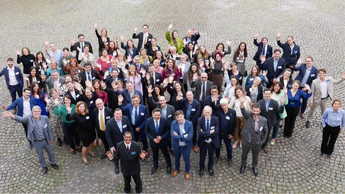 ENNHRI group photo with around 70 people - both members and Secretariat staff alike - looking up at the camera. The photo is taken from above and is in a courtyard.