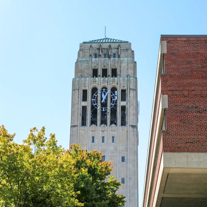 Burton Tower alongside a tree and part of the Modern Languages Building at the University of Michigan