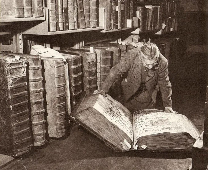 Black and white photo of woman looking at a giant book of records.