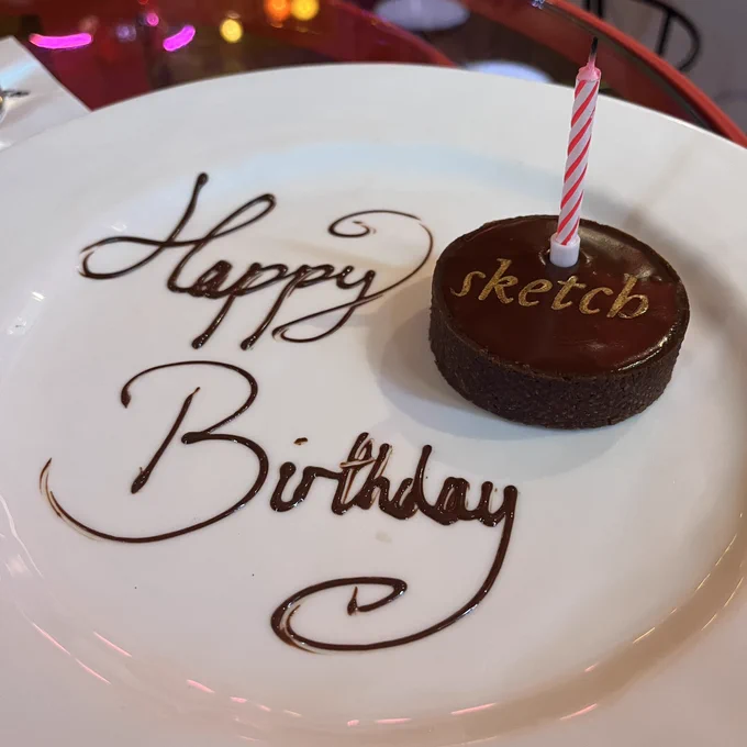 A chocolate banoffee tart from Sketch London with a birthday candle in it. The plate has Happy Birthday written on it in chocolate sauce