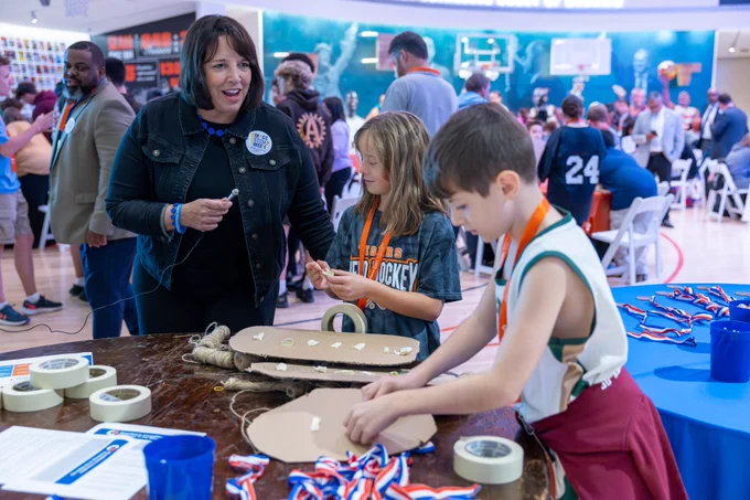 Lieutenant Governor Driscoll talks with students working at a table.