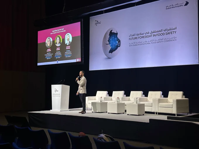 Matheus Cezarotto giving a talk at the Dubai International Food Safety Conference, onstage with slides behind him