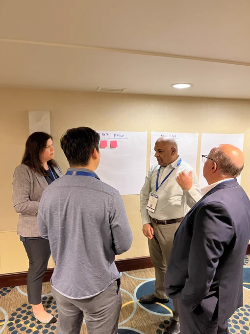 Participants standing in front of posters on the wall with their brainstorming ideas on pink post-its.