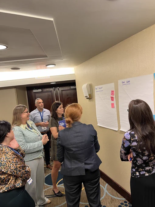 Participants standing in front of posters on the wall with their brainstorming ideas on pink post-its.