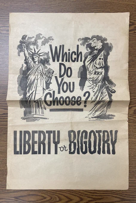 Poster saying “which do you choose? Liberty or bigotry” with flaming images of the Statue of Liberty and a klansman.