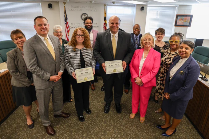This is a group photo of State Board Members and Dr. Wright smiling with the two National Distinguished Principals of the Year, who are holding certificates.