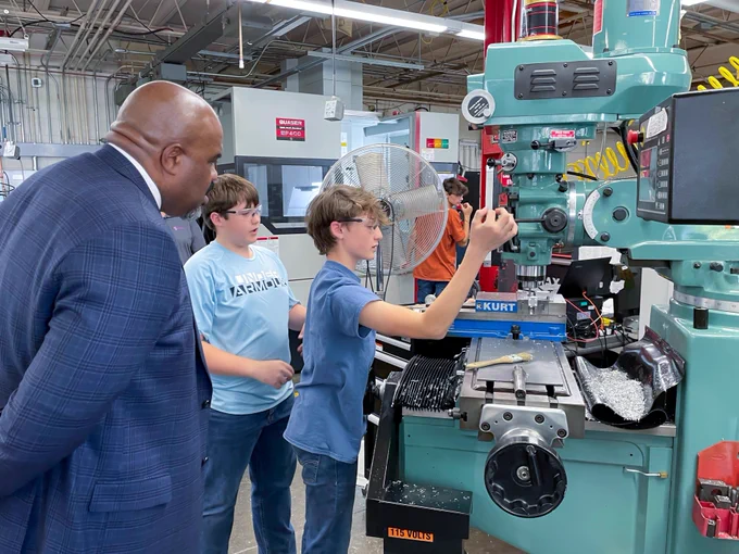 Education Secretary Tutwiler watches as students show him how to use machines in a lab.