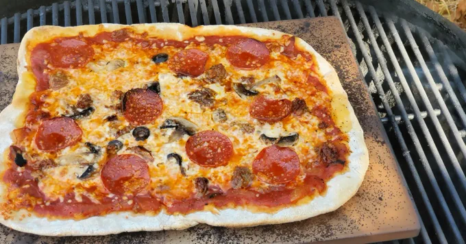 Homemade Pizza. Made in a Primo Ceramic lump charcoal Grill, cooked on a pizza/bread stone with red sauce, pepperoni, mozzarella cheese, parmesan cheese, mushrooms & black olives. 