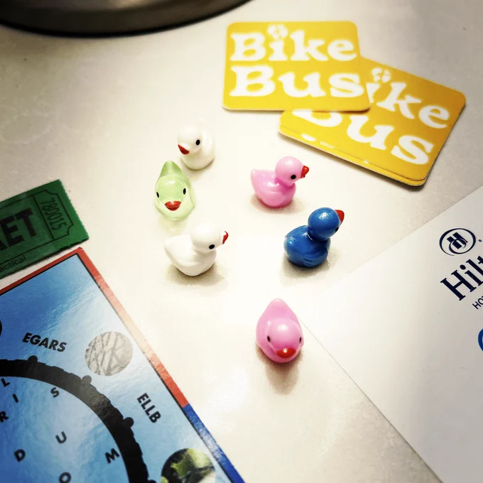 Tiny, glass ducks in colors of white, pink, blue and green gather together on a nightstand tabletop.