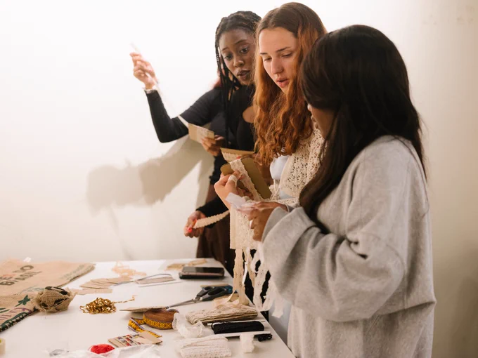 Three people holding fabric samples. 