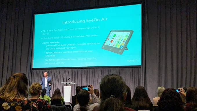 A man standing presenting a communication aid.