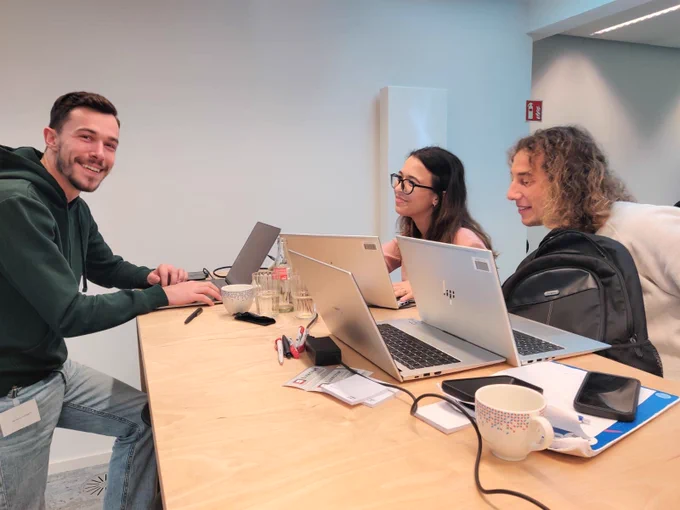a young team smiling, in front of their computers