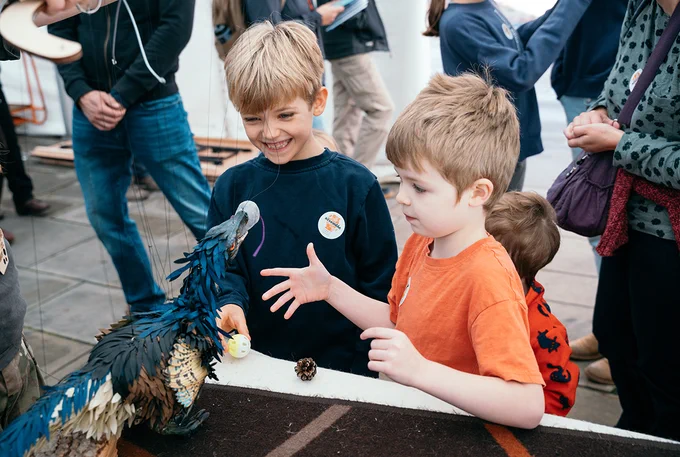 Two children are laughing and playing with a puppet.