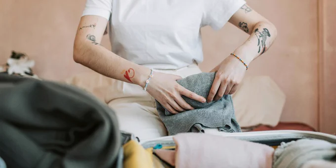 Person folding clothes to pack in a suitcase.
