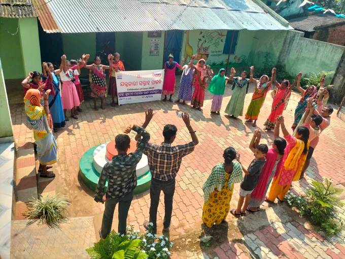 Large group of people holding hands in a circle outside
