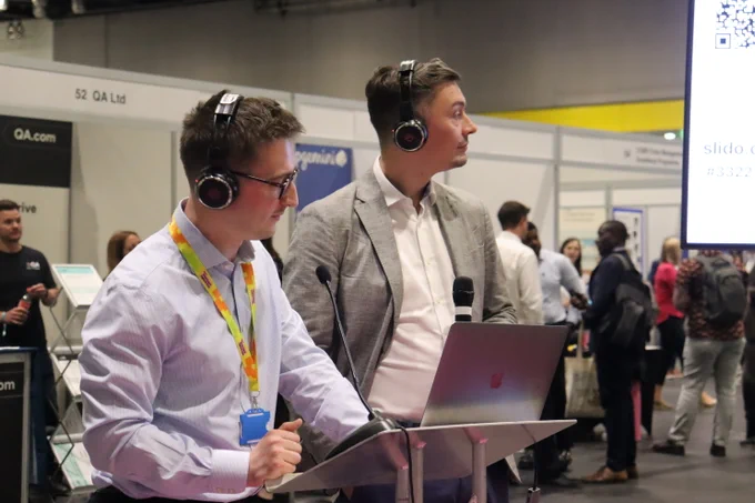 Civil servants at Civil Service Live events with headphones, watching a demo. 