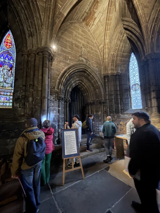 People exploring Glasgow Cathedral with torches and looking for stonemasons' marks.