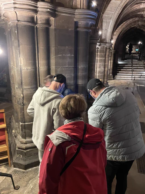 People exploring Glasgow Cathedral with torches and looking for stonemasons' marks.