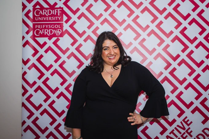 An image of Jess in front of the Creative Cardiff logo