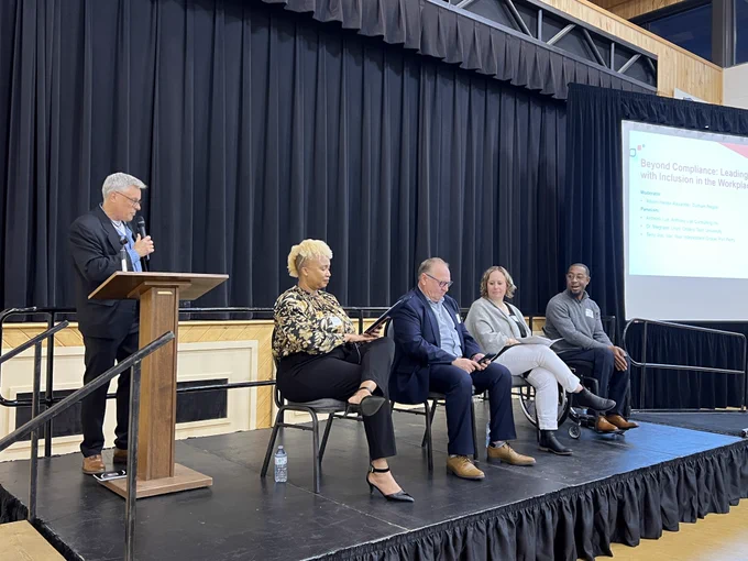 Emcee Dan Pollard introducing from left to right panel moderator Allison Hector-Alexander and panelists Terry Vos, Dr. Meghann Lloyd and Anthony Vue