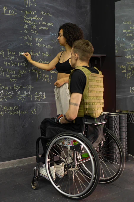 Two people writing on a chalkboard.