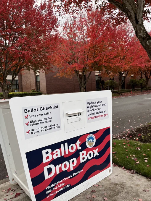 Ballast box with Beaverton City Library main in the background and 4 maple trees with orange and red leaves.