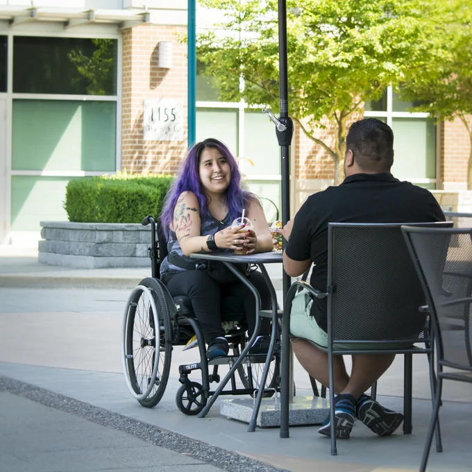 Person in wheelchair at patio table.