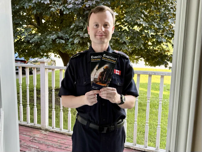 Whitby Fire staff on a resident's porch holding pamphlets promoting fire safety.