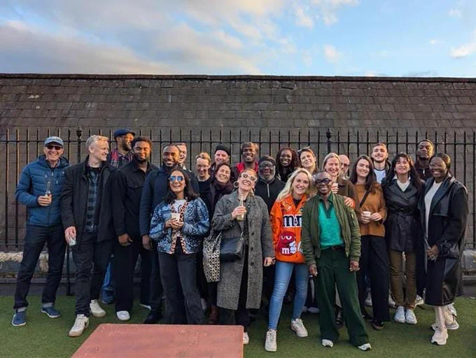 Over 20 of the Spark Inside team having a drink in the evening sun under a blue sky