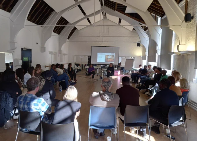 Spark Inside team listening to Amy Frost being interviewed in a large sunlit room