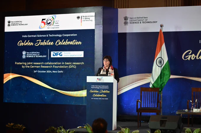 Vice President DFG Prof. Karin Jacobs standing in front of a lectern highlighting achievements from 20 years of DFG DST collaboration.