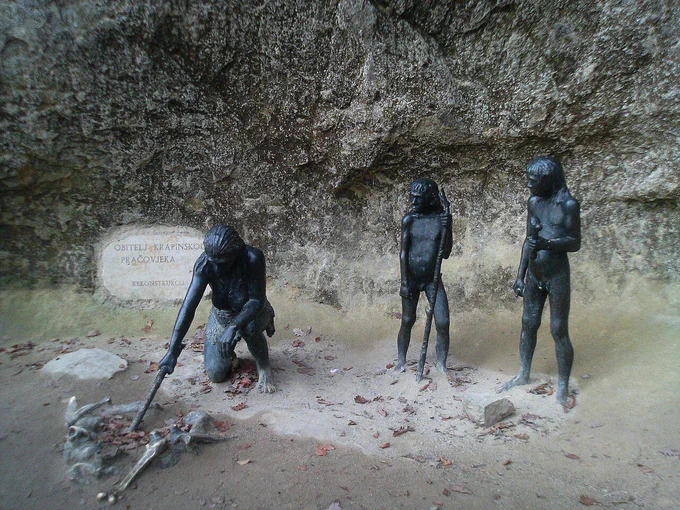 Statues reconstructing a Palaeolithic scene at Krapina. Two Neanderthals stand whilst a third tends to a fire.