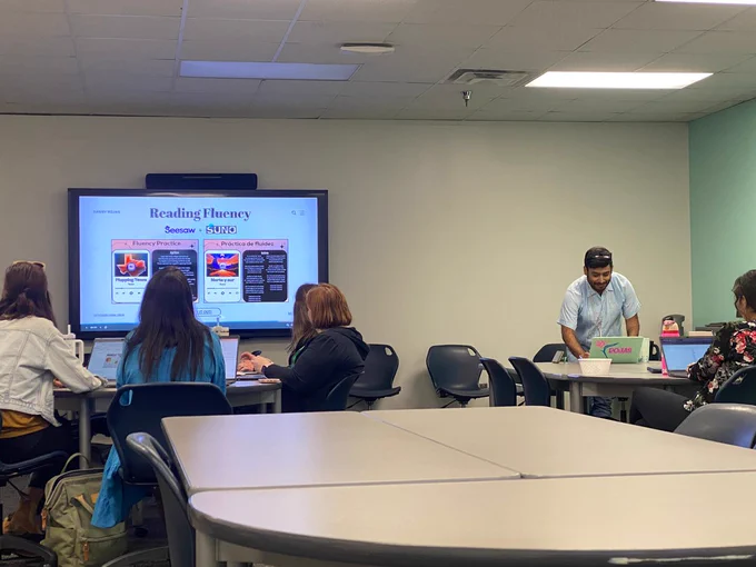 Presenter sharing information on TV screen while participants watch while sitting at tables