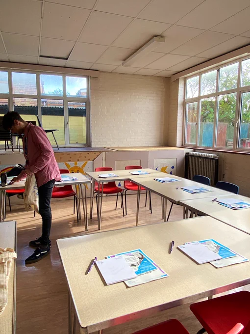 A bright and cheerful space with tables, chairs, and RCE Wellbeing Hub merchandise.