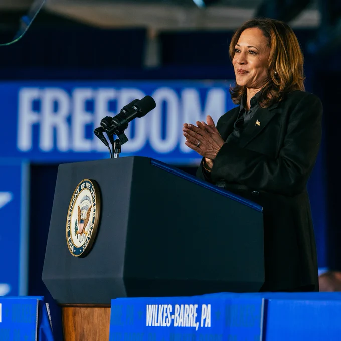 Vice President Kamala Harris stands at a podium against a blue backdrop that reads, "Freedom."