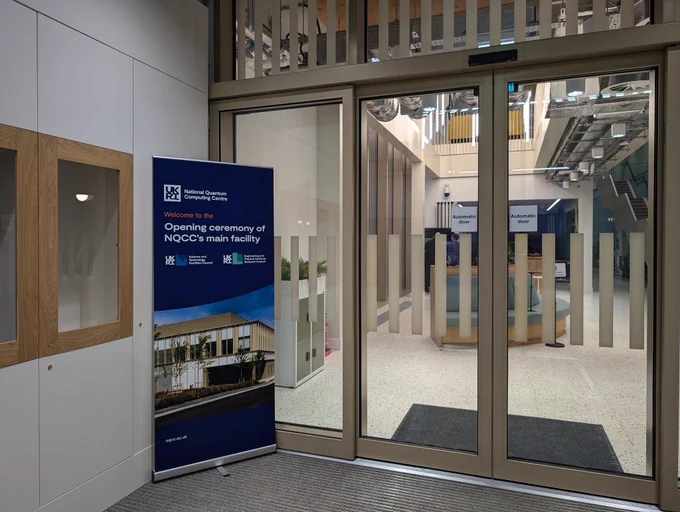 Glass doors with a banner that says Opening ceremony of the NQCC's main facility.