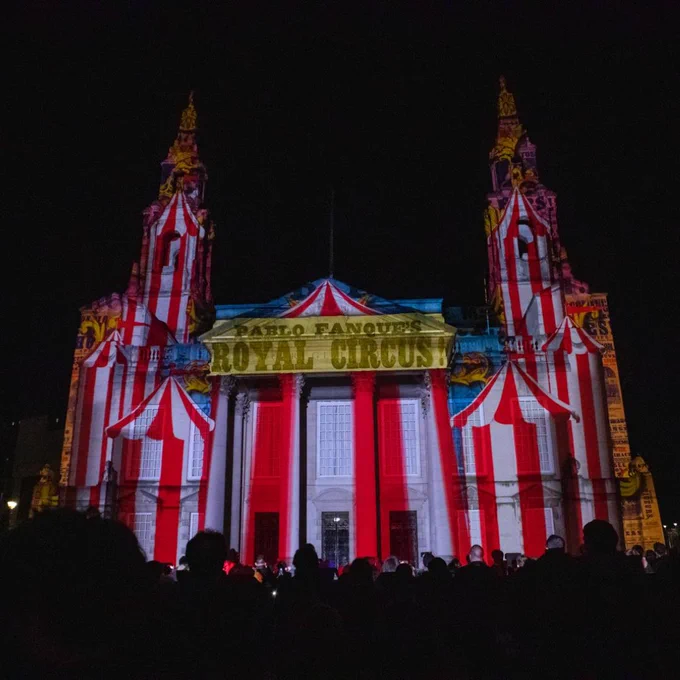 Out of the Aire at Millennium Square. Leeds Civic Hall is projected with red and white circus big top tents and a yellow sign that reads: "Pablo Fanque's Royal Circus!"