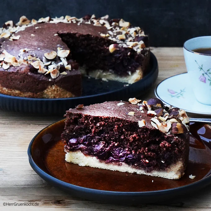 Nusskuchen mit Mürbeteig. Auf dem Mürbeteig Kirschen mit Kirschwasser und Zimt. Darauf ein dunkler Haselnussteig.