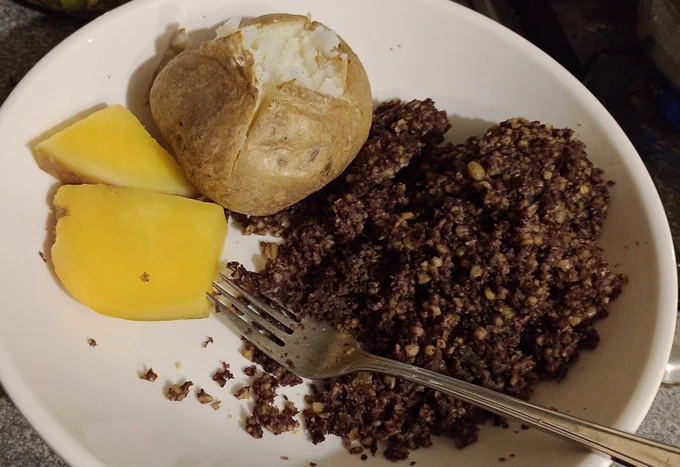 A plate with a baked potato, a couple of slices of steamed swede, and a lot of haggis