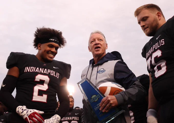GLVC commissioner Jim Naumovich presents the conference champion trophy to the UIndy football team.