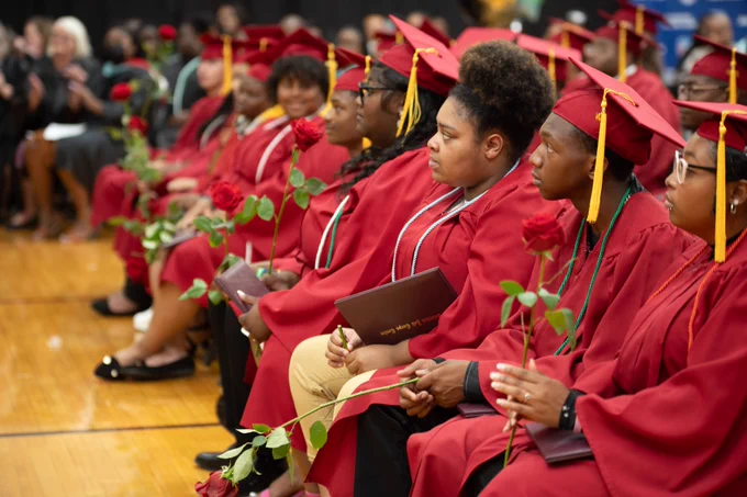 An audience of Job Corps graduates sit in their regalia during their graduation ceremony.